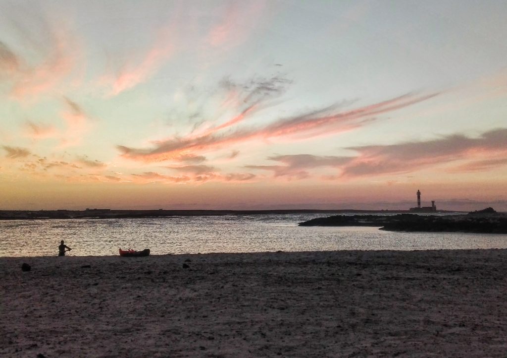 tramonto sulla spiaggia con faro in lontananza